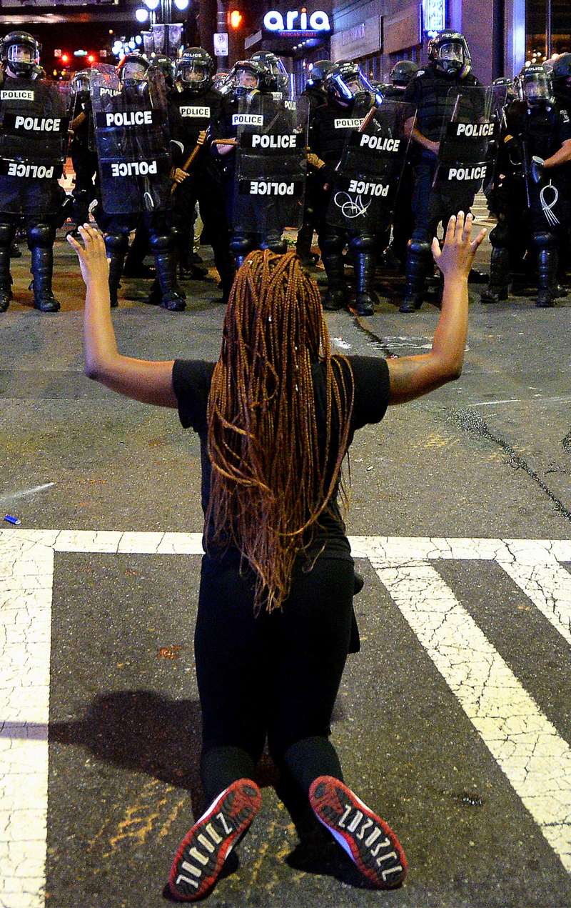 A protester places her arms in the air while on her knees in front of officers in riot gear at the intersection near the Epicentre in Charlotte, N.C., on Sept. 21, 2016.Jeff Siner/Charlotte Observer/TNS via Getty Images